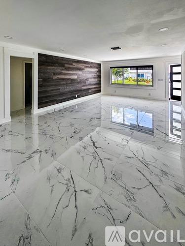 A spacious room with marble flooring and a wooden accent wall.