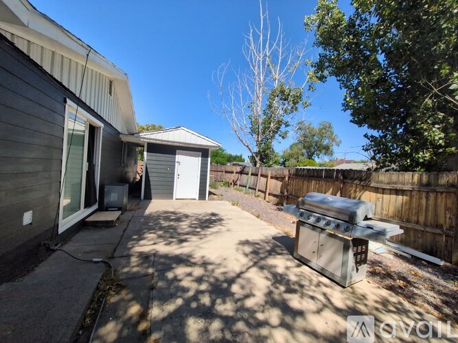 A backyard with a grill and a tree.