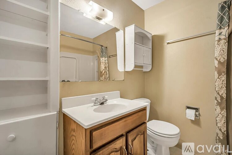 A bathroom with a toilet, sink, and mirror.