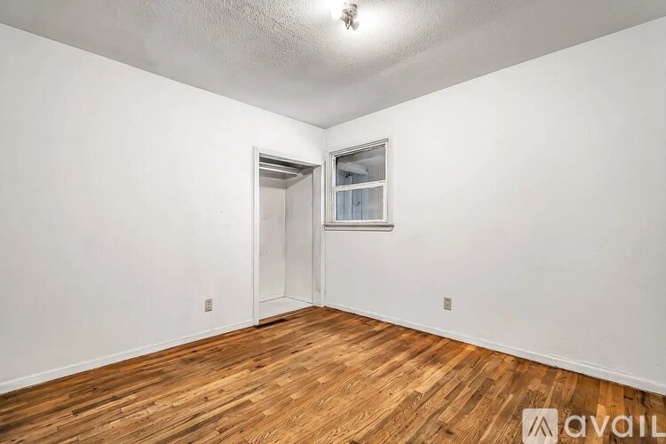 A room with wooden flooring and a white door leading to another room.