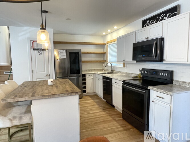 A kitchen with white cabinets and black appliances.