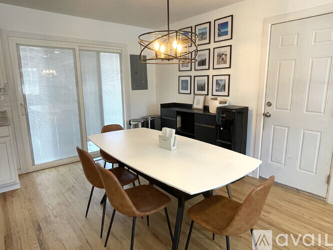 A dining room with a white table and brown chairs.
