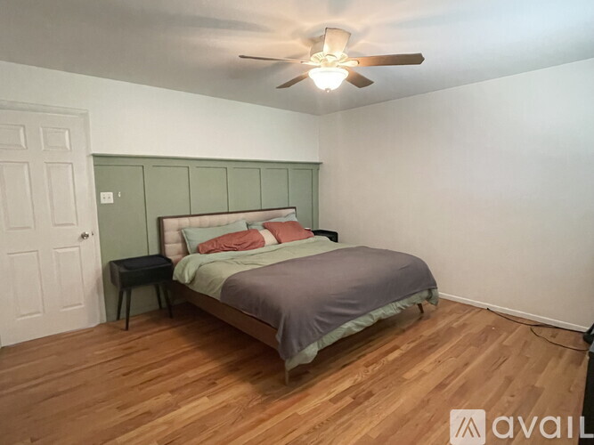 A bedroom with a bed, nightstand, and a ceiling fan.