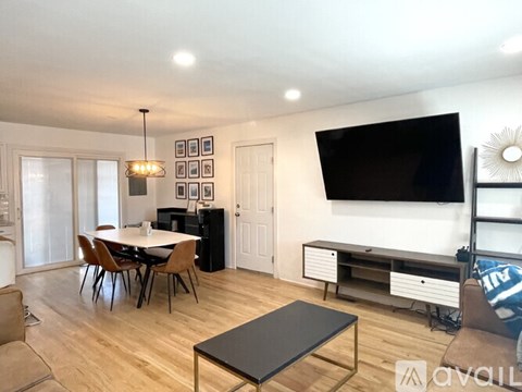 A living room with a black coffee table and a flat screen TV mounted on the wall.