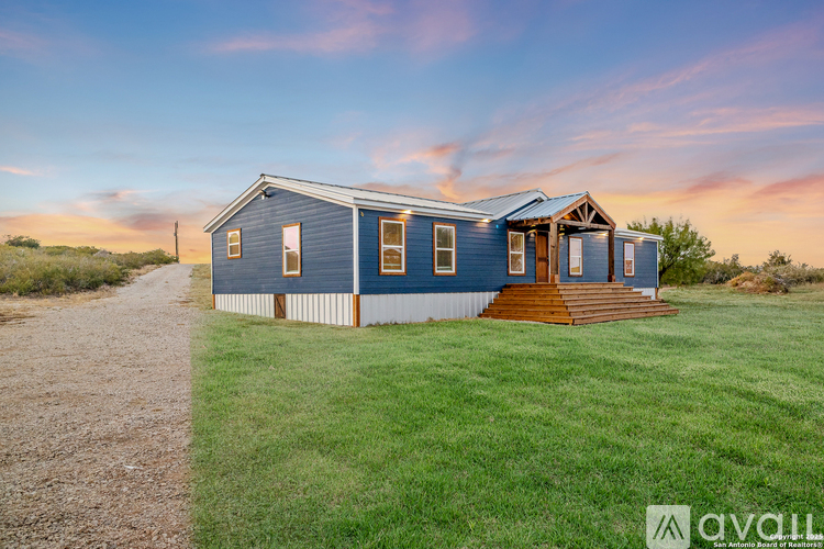 A blue house with a wooden porch is available for sale.