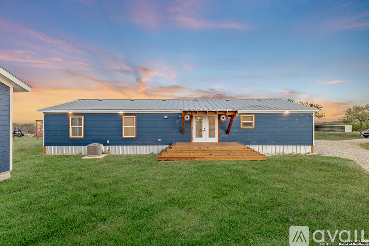A blue house with a white fence and a wooden deck in front.