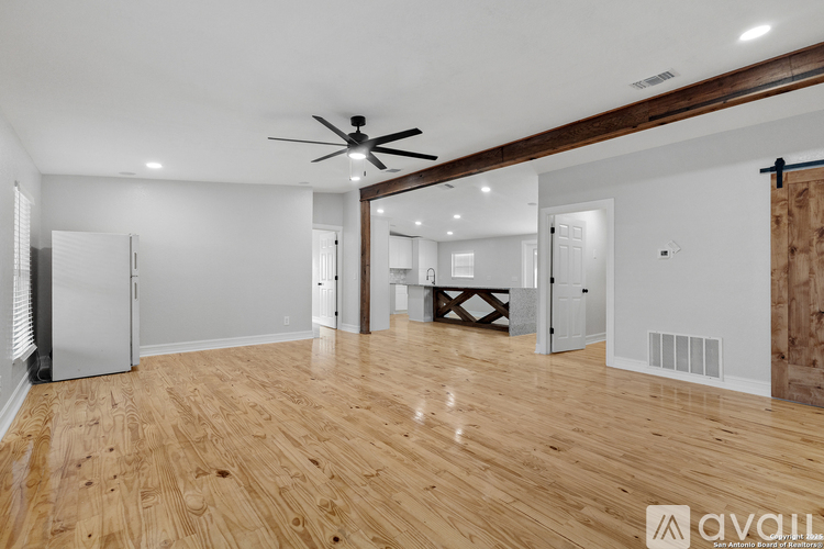 A spacious room with wooden flooring and a ceiling fan.