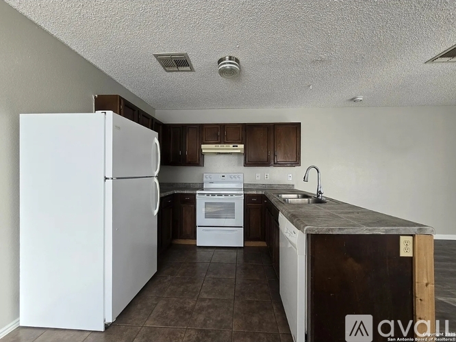 A kitchen with white appliances and brown cabinets.