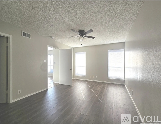 A spacious room with a ceiling fan and wooden flooring.
