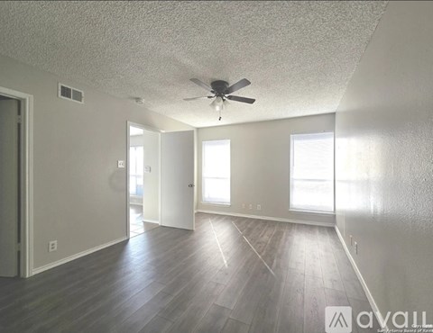 A spacious room with a ceiling fan and wooden flooring.