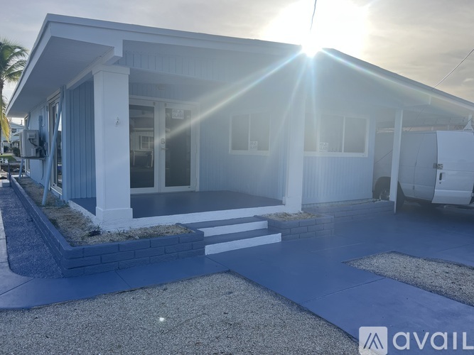 A house with a blue front yard and a white exterior is shown.