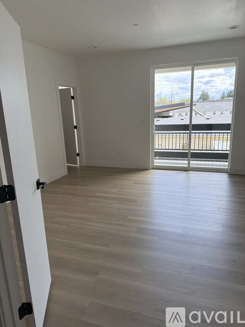 A room with wooden flooring and a large window overlooking a parking lot.