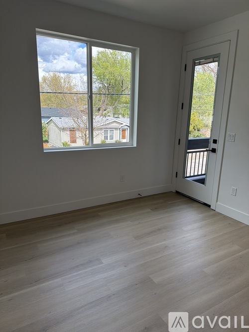 A room with a large window and a door leading to a balcony.