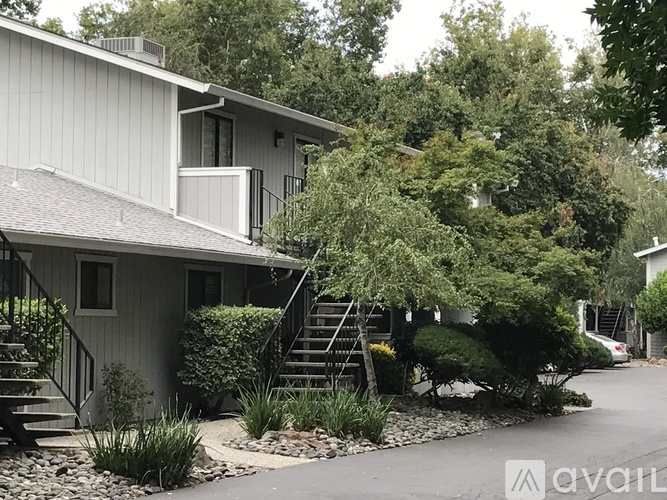 A house with a grey roof and a tree in front of it.