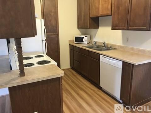 A kitchen with wooden cabinets and a white stove top oven.