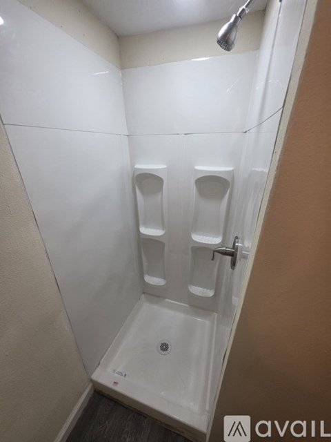 A small white bathroom with a shower and two urinals.