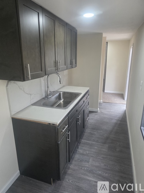 A kitchen with black cabinets and a white sink.