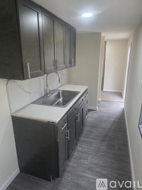 A kitchen with black cabinets and a white sink.