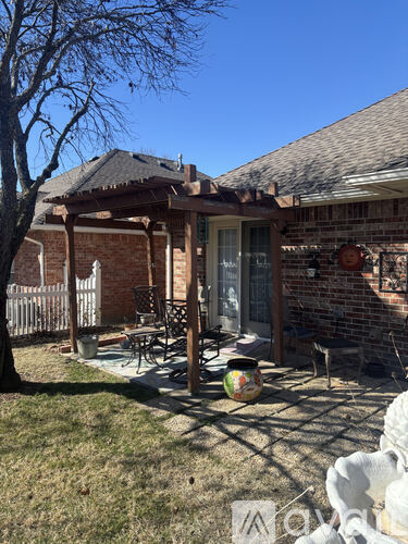 A patio with a table and chairs is covered by a pergola.