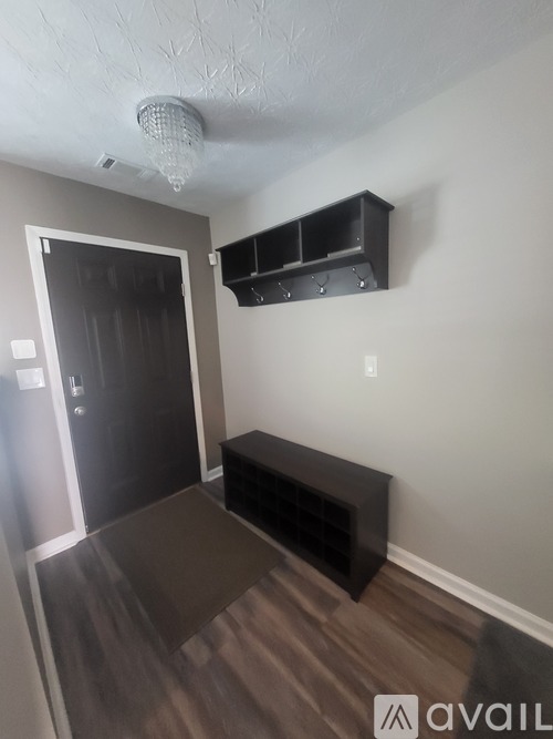 A room with a wooden floor and a black bench under a light fixture.