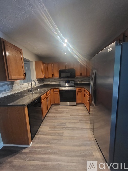 A kitchen with wooden cabinets and a stainless steel refrigerator.