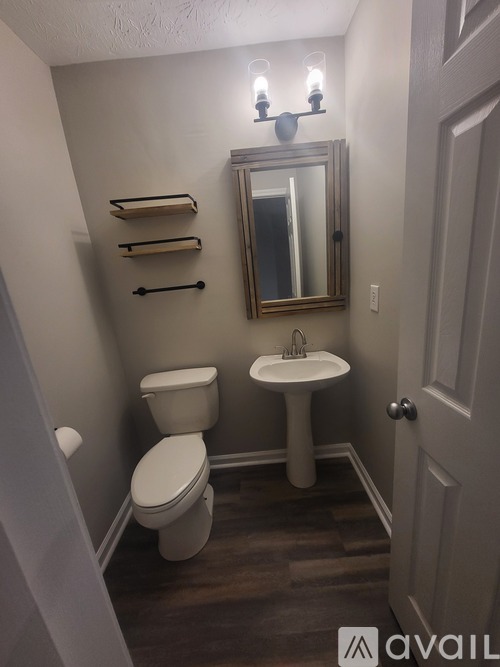 A bathroom with a toilet, sink, and mirror.
