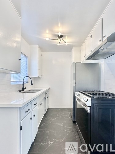 A kitchen with white cabinets and a black stove top oven.