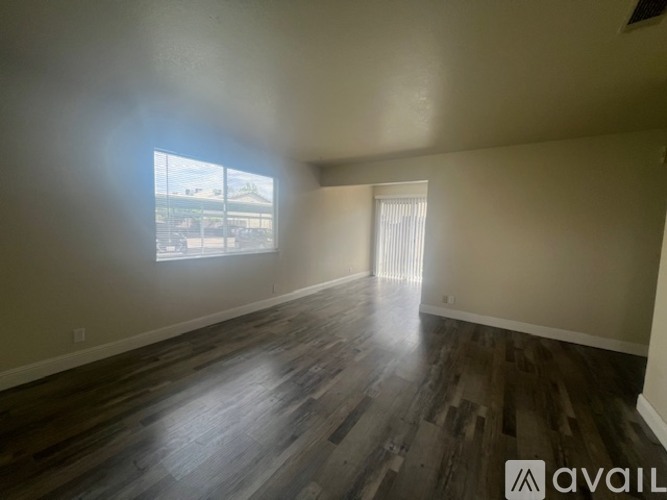 A room with wooden flooring and a window letting in light.