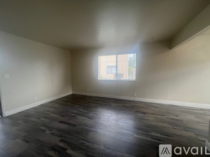 A room with wooden flooring and a window letting in light.