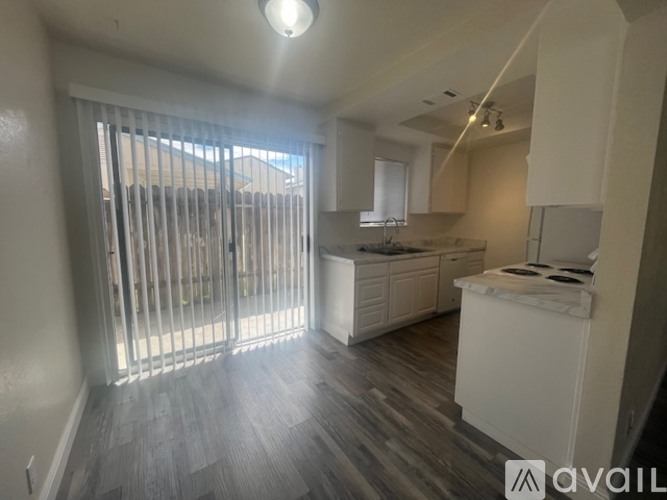 A kitchen with white cabinets and a wooden floor.