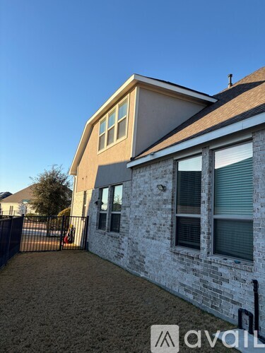 A house with a brown roof and a white brick wall with a black gate in front.