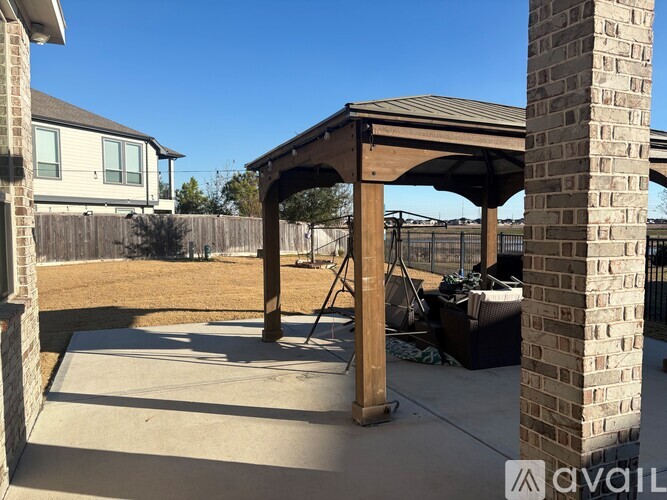 A patio with a wooden pergola and a brick pillar.