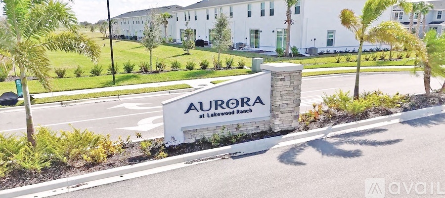 A white sign with the word "Aurora" on it is in front of a building.