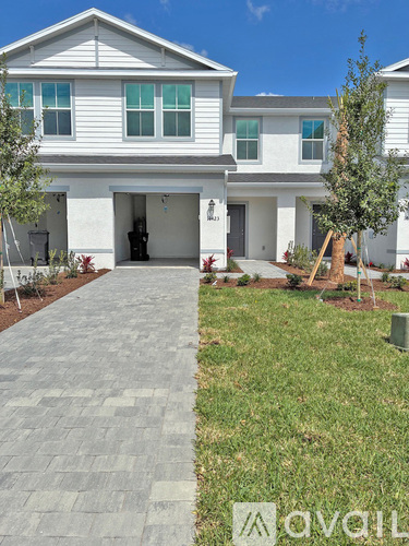 A white two-story house with a grey walkway in front.