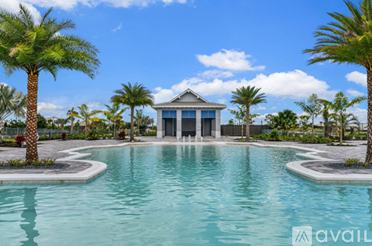 A pool surrounded by palm trees and a house in the background.