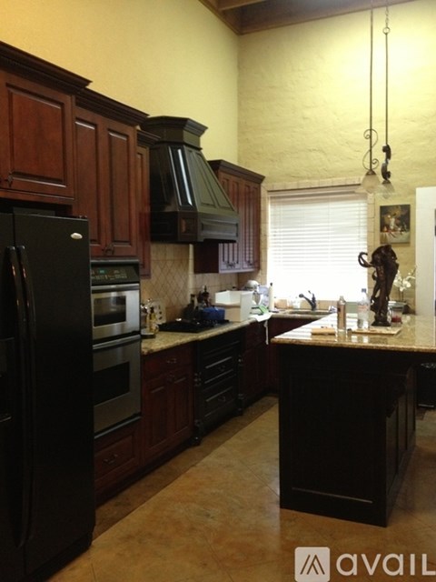 A kitchen with dark wood cabinets and black appliances.