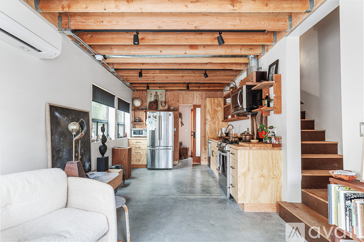 A living room with a white couch and a kitchen area with wooden cabinets.