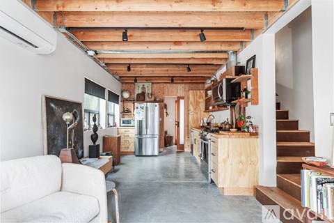 A living room with a white couch and a kitchen area with wooden cabinets.