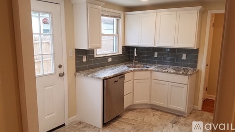 A kitchen with white cabinets and a marble countertop.
