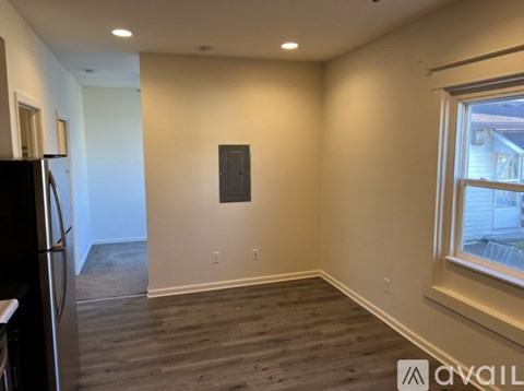 A room with wooden flooring and a window on the right side.