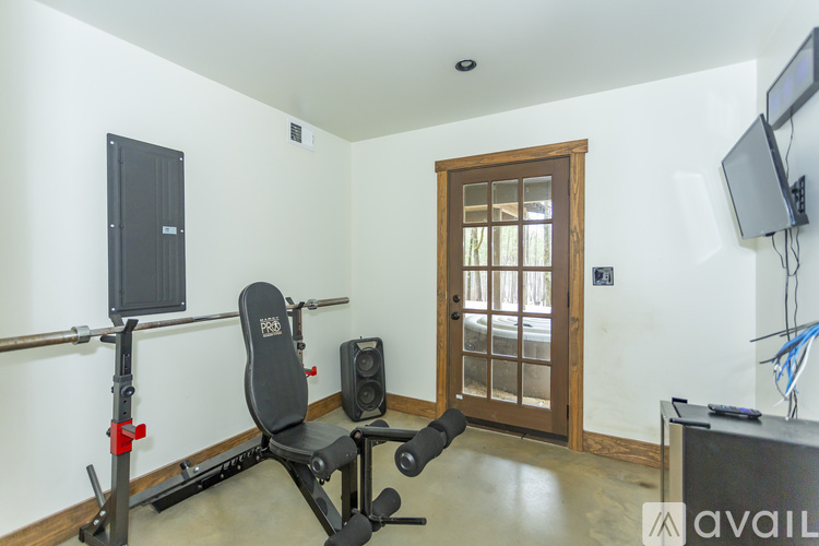 A gym room with a weight bench, a television, and a door.