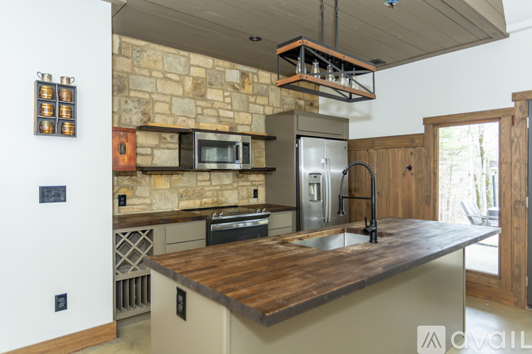 A kitchen with a stone wall and a wooden counter top.