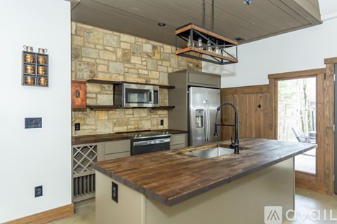 A kitchen with a stone wall and a wooden counter top.
