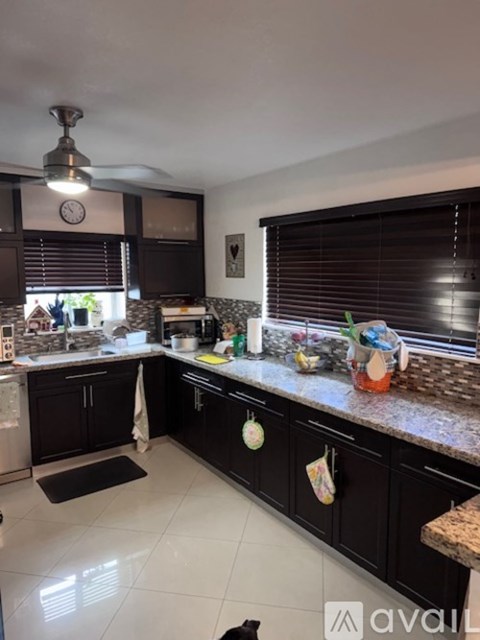 A kitchen with black cabinets and a marble countertop.
