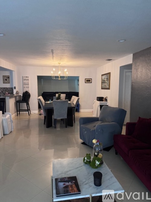 A living room with a grey couch, a coffee table, and a dining table set up.