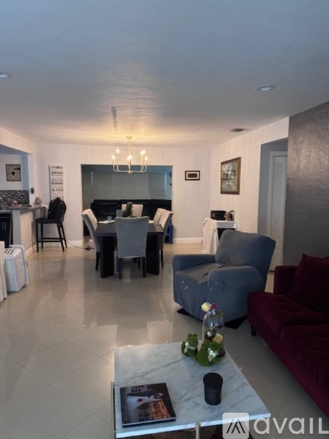A living room with a grey couch, a coffee table, and a dining table set up.
