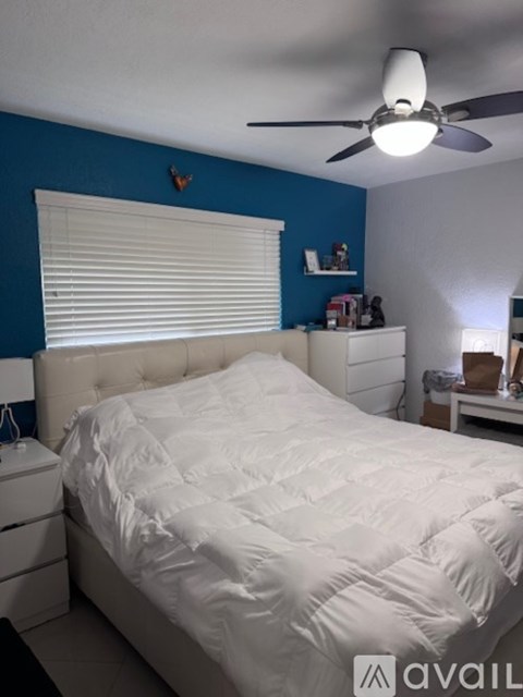 A bedroom with a white bed and a ceiling fan.