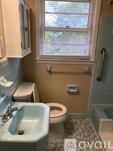 A bathroom with a toilet, sink, and window.