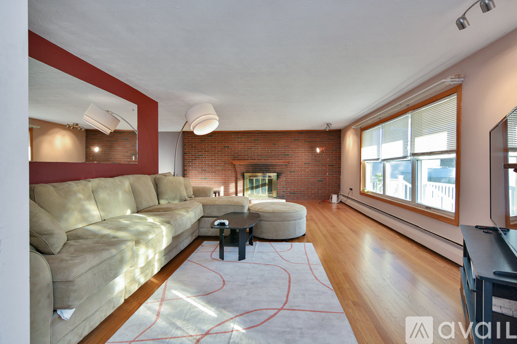 A living room with a tan couch and a red rug.