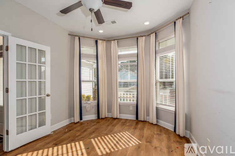 A room with a ceiling fan and sliding glass doors.